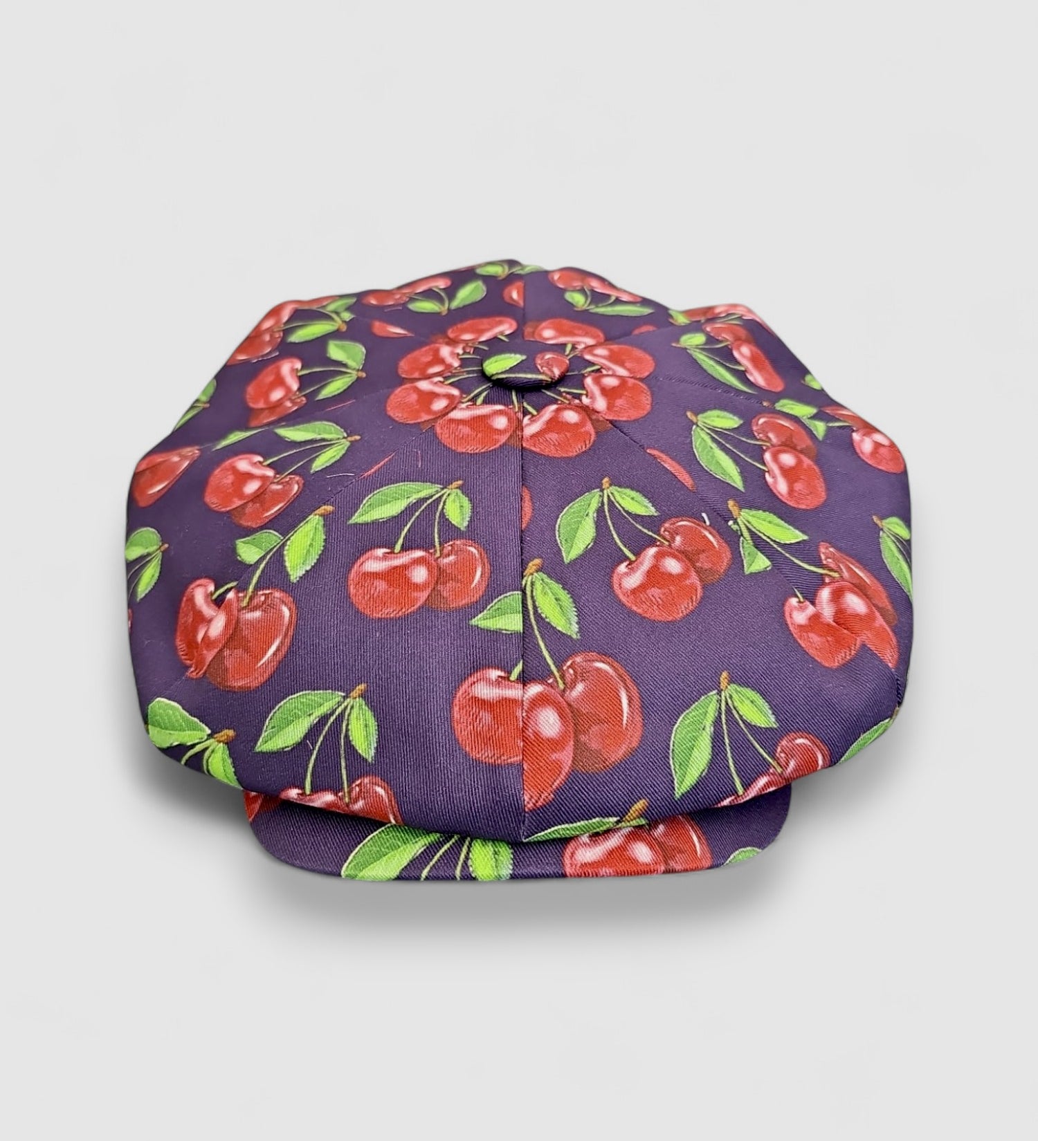 Midnight blue oversized Bakerboy cap with bold exploding cherry print — Cherry Pop hat from the Leigh Francis x Mister Miller collection, featuring curved peak and 70s-style swirl lining. front view