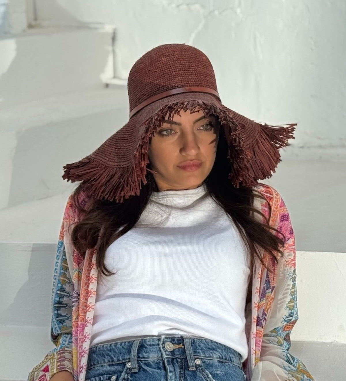 a woman wearing the Brown raffia straw wide brim hat with fringe and leather band, by Mister Miller.