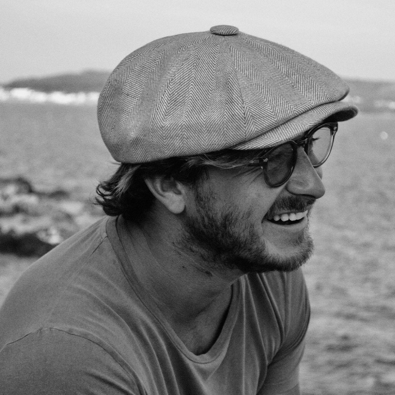 A man wearing a Bakerboy cap in neutral herringbone Irish linen — Riley’s Dunes by Mister Miller, a lightweight summer hat.