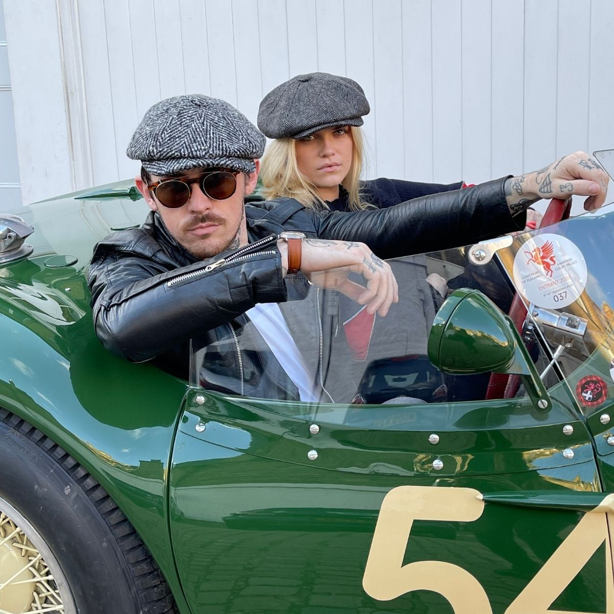 a man and woman in a classic car wearing cool bakerboy caps