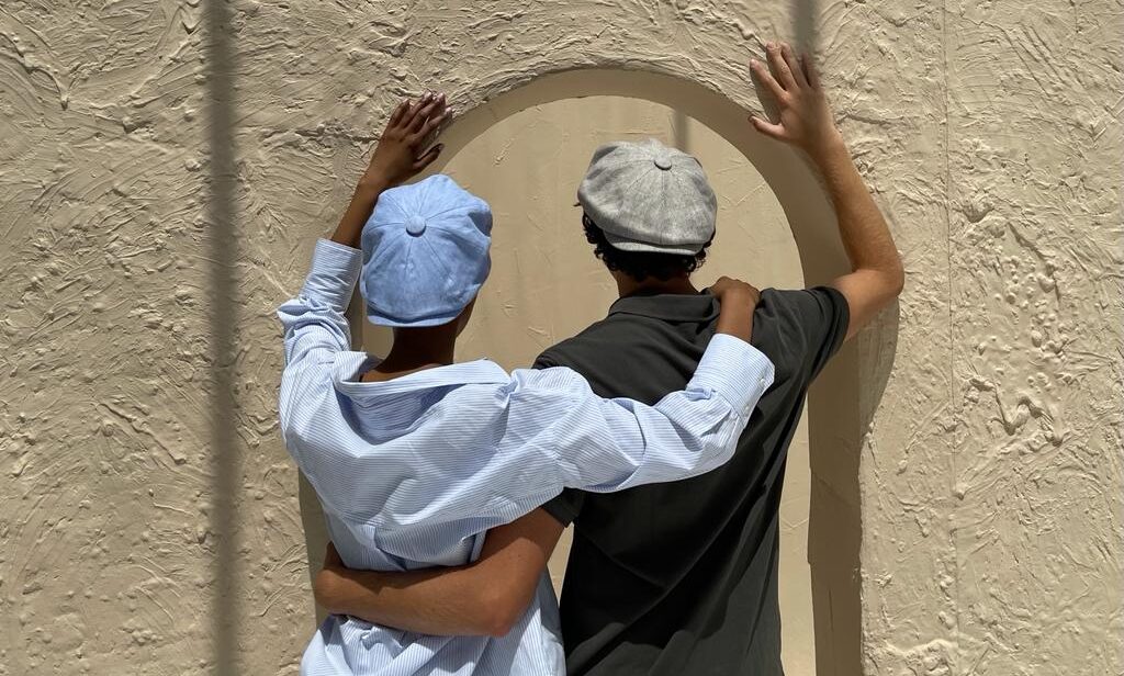 a man and a woman wearing Bakerboy caps in Irish linen herringbone — Riley Skies by Mister Miller, a breathable summer hat handmade in Britain. 