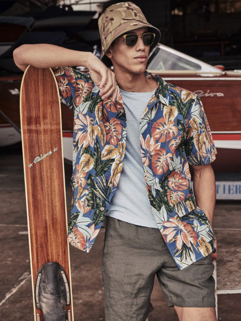 MAN wearing a ket hat and sunglasses, holding a vintage Riva waterski