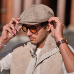 A man wearing a Bakerboy cap in beige herringbone Merino lambswool — Riley’s Peregrine by Mister Miller, handmade in Britain. 