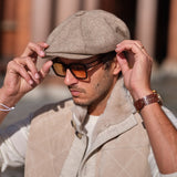 A man wearing a Bakerboy cap in beige herringbone Merino lambswool — Riley’s Peregrine by Mister Miller, handmade in Britain. 