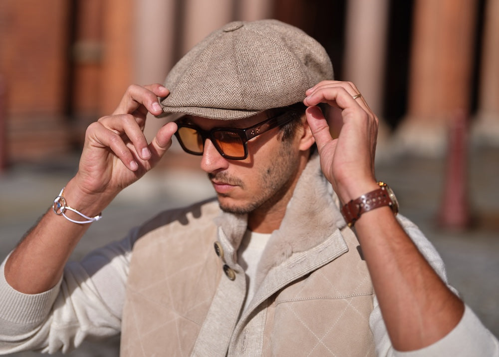 A man wearing a Bakerboy cap in beige herringbone Merino lambswool — Riley’s Peregrine by Mister Miller, handmade in Britain. 