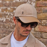 a man wearing a Camel cashmere herringbone baseball cap with tan leather peak by Mister Miller.