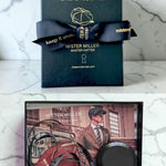 Mister Miller hat box with a bow and image of a tape measure on a card featuring a man wearing a hat