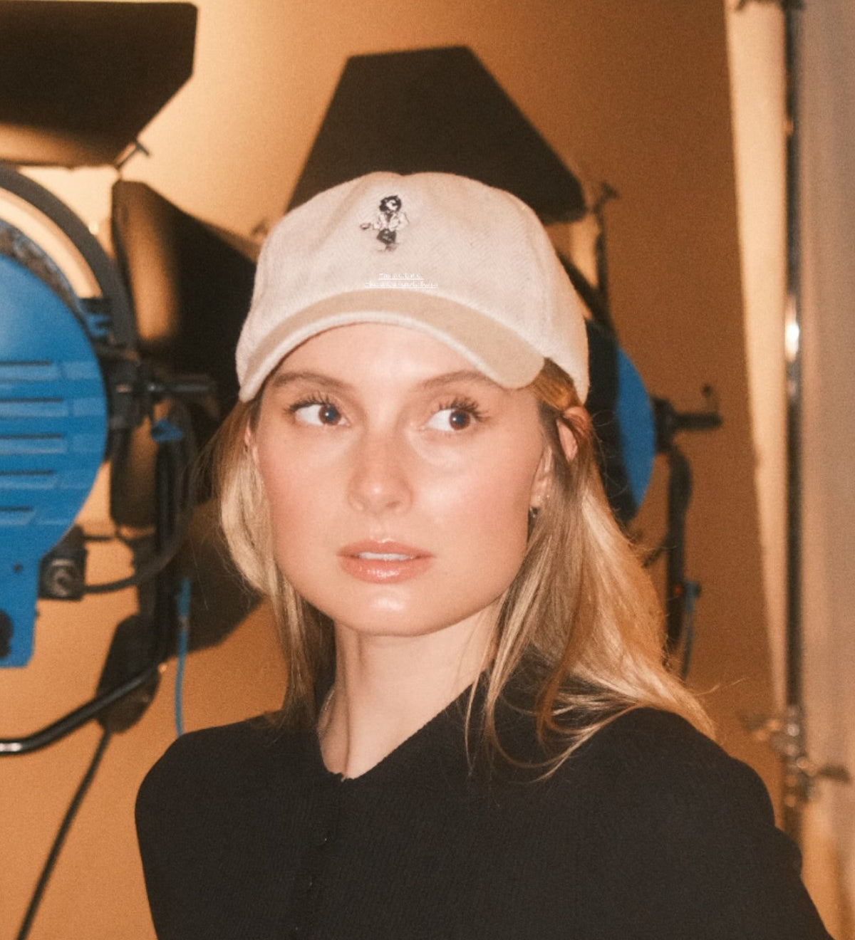 Woman wearing a beige wool baseball cap with Monty lion embroidery and striped green satin lining. A limited-edition Mister Miller x Gentleman Racer hat.