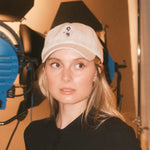 Woman wearing a beige wool baseball cap with Monty lion embroidery and striped green satin lining. A limited-edition Mister Miller x Gentleman Racer hat.