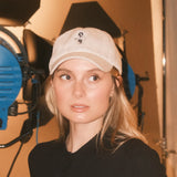 Woman wearing a beige wool baseball cap with Monty lion embroidery and striped green satin lining. A limited-edition Mister Miller x Gentleman Racer hat.