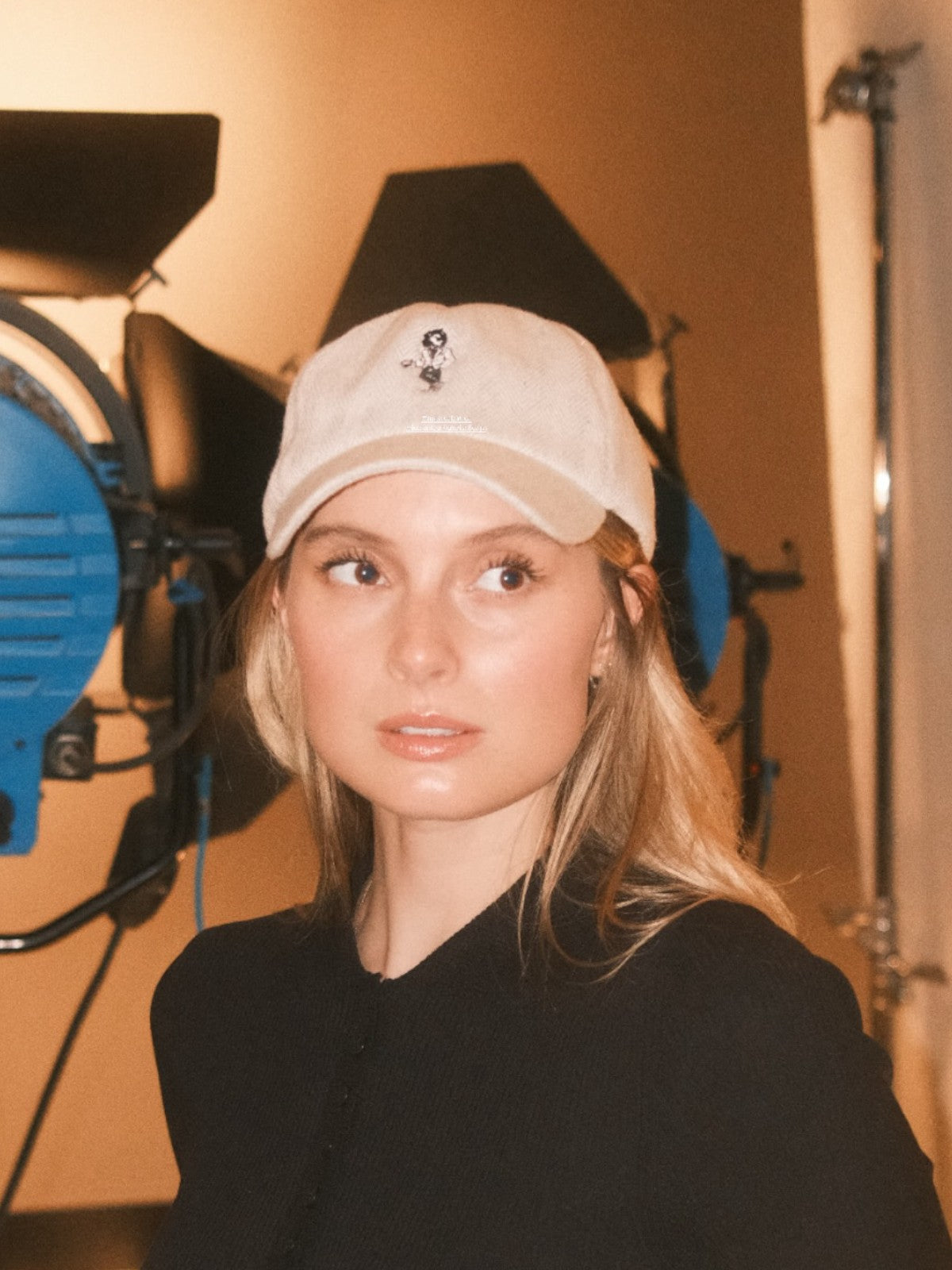Woman wearing a beige wool baseball cap with Monty lion embroidery and striped green satin lining. A limited-edition Mister Miller x Gentleman Racer hat.