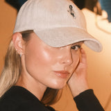 Woman wearing a beige wool baseball cap with Monty lion embroidery. A limited-edition Mister Miller x Gentleman Racer hat.