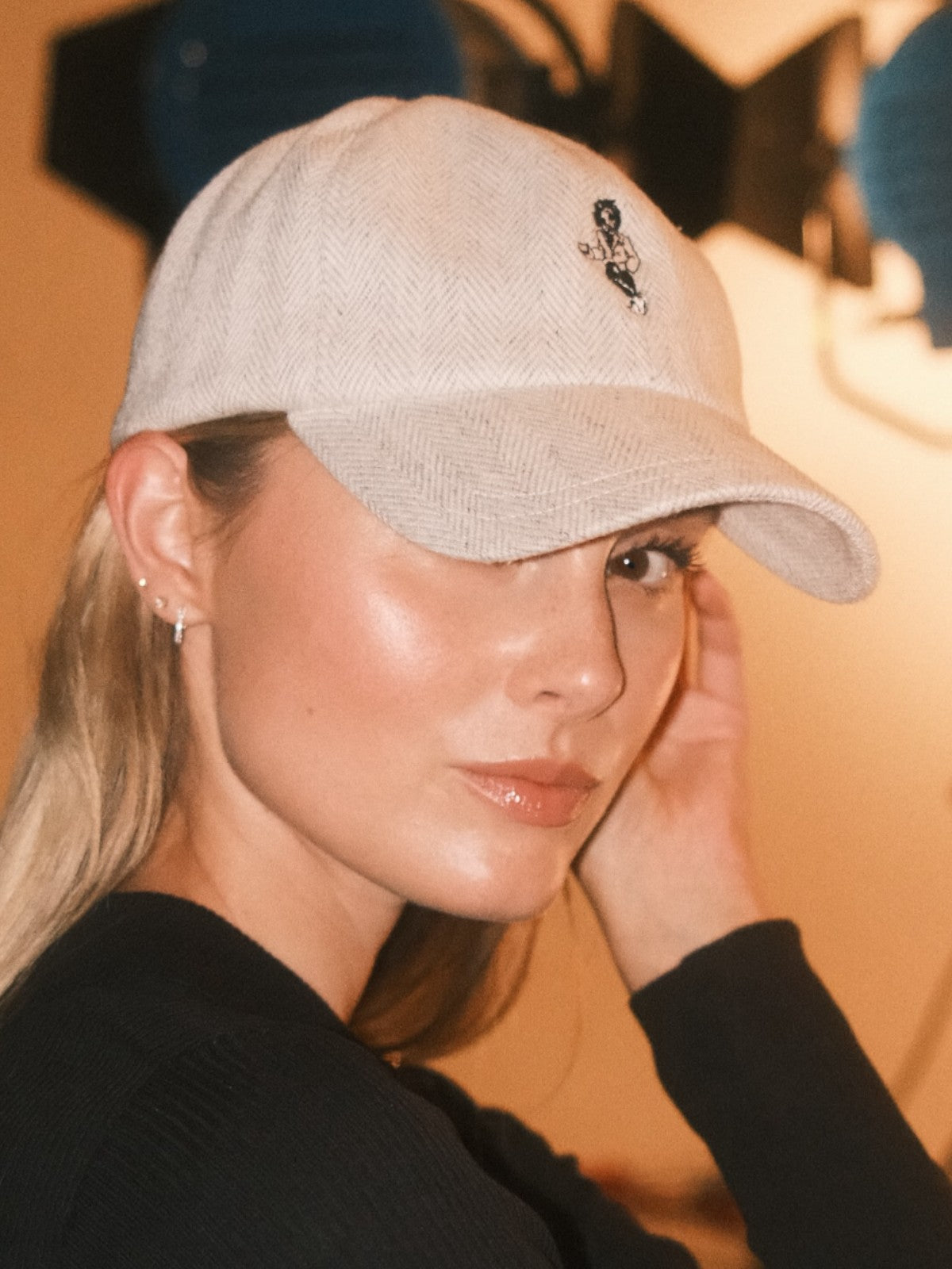 Woman wearing a beige wool baseball cap with Monty lion embroidery. A limited-edition Mister Miller x Gentleman Racer hat.