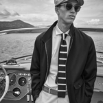Man in a bakerboy cap on a boat with a scenic background