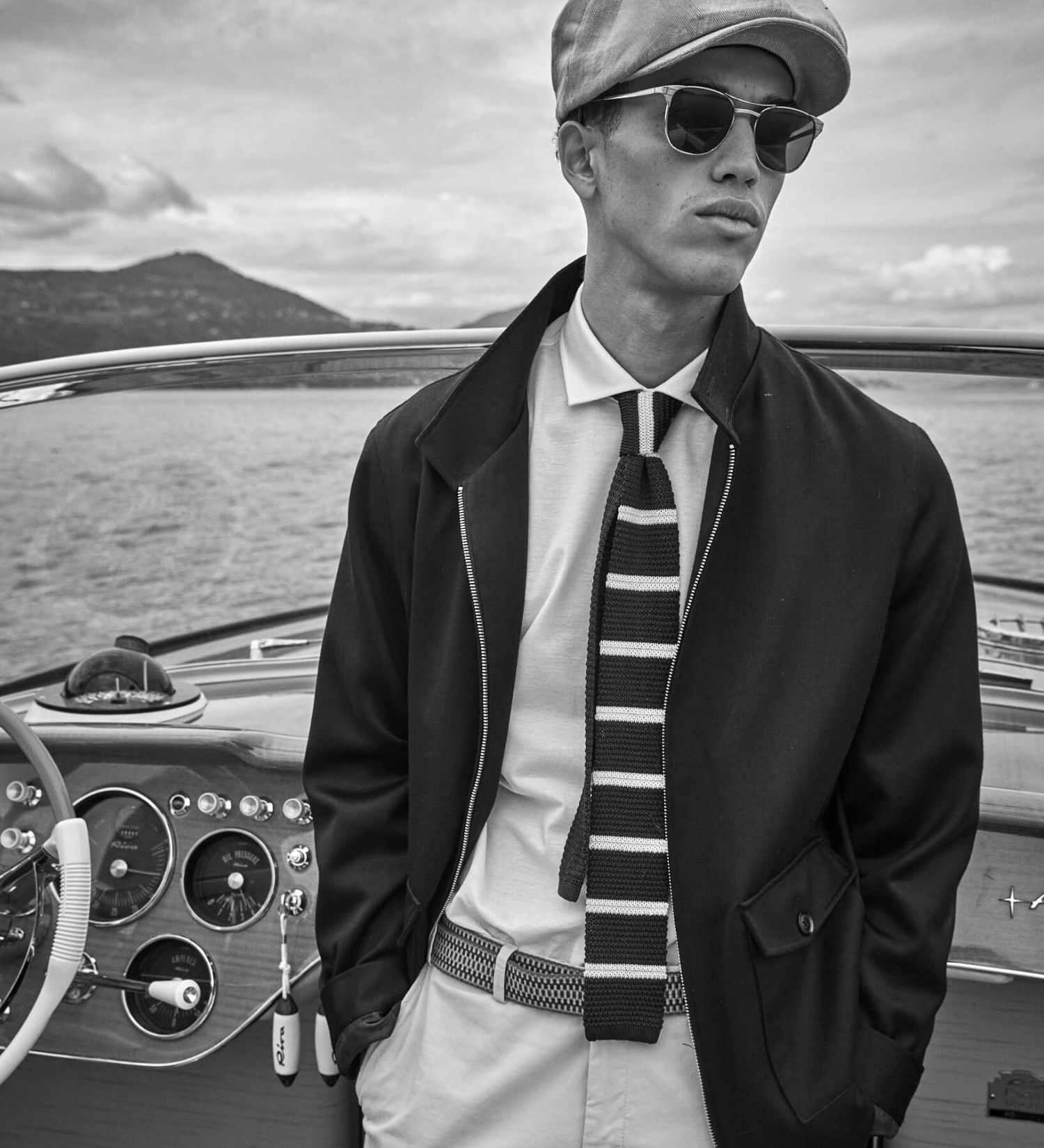 Man in a bakerboy cap on a boat with a scenic background