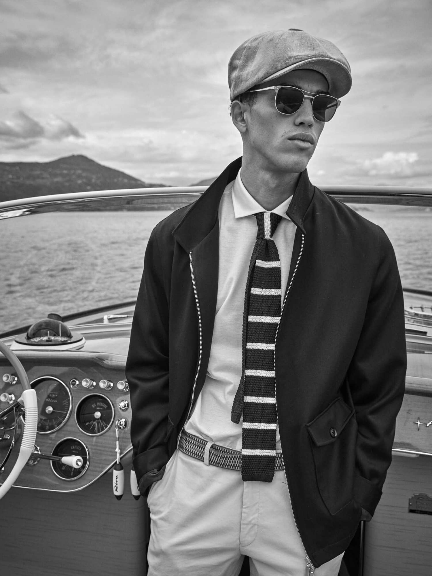 Man in a bakerboy cap on a boat with a scenic background