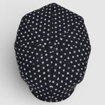 Navy Bakerboy cap with white polka dots on a grey background