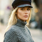 Woman wearing a black cap and gray sweater in an urban setting