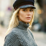 Woman wearing a black cap and gray sweater in an urban setting