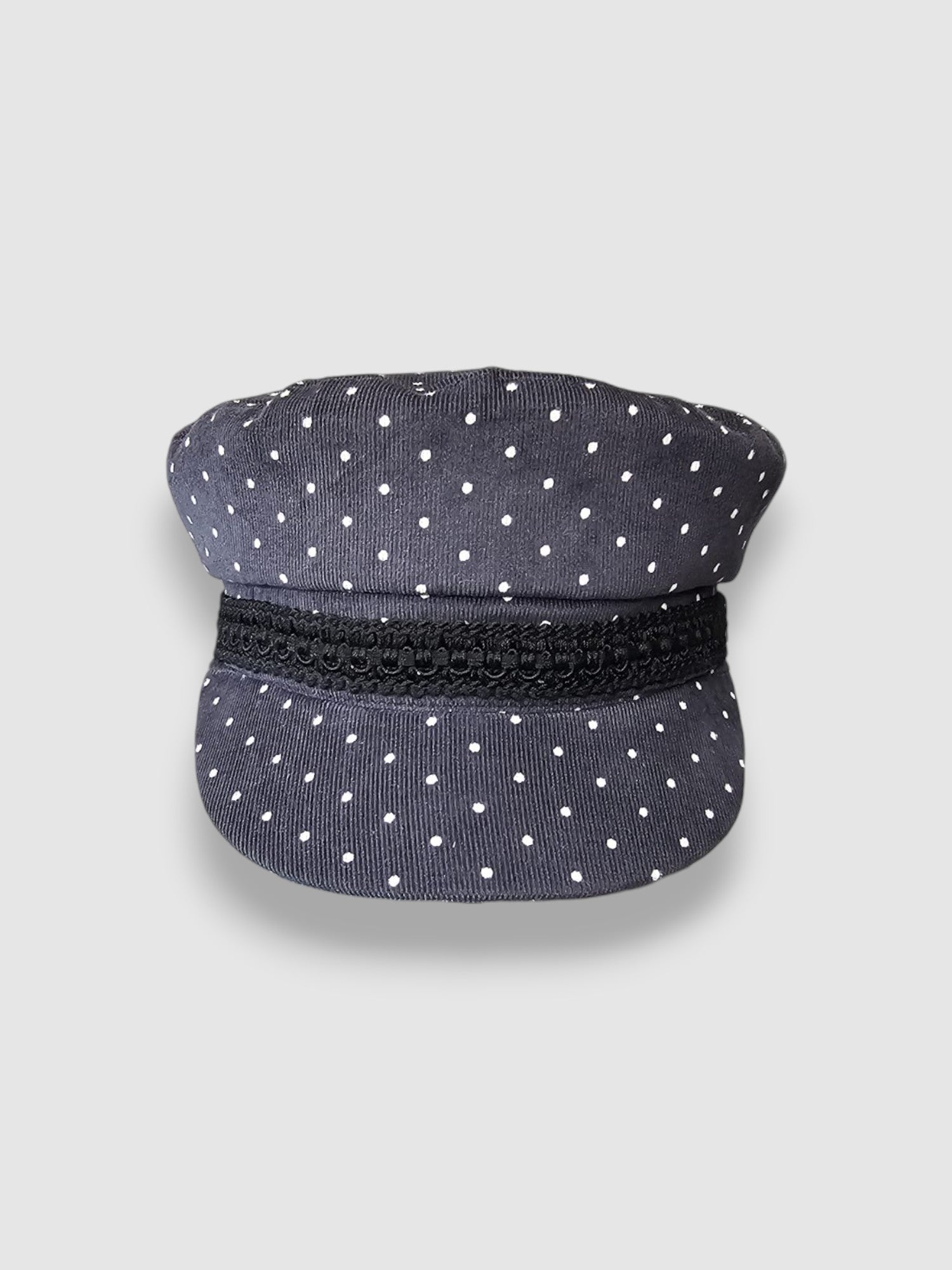 Navy blue cap with white polka dots and a black band on a light gray background