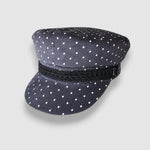 Navy blue cap with white polka dots and a black band on a light gray background