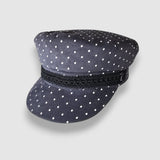 Navy blue cap with white polka dots and a black band on a light gray background