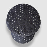 Navy blue cap with white polka dots on a light gray background