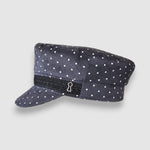 Polka dot cap with a black band featuring a keyhole design on a light gray background