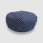 Navy blue cap with white polka dots on a light gray background