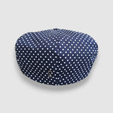 Navy blue cap with white polka dots on a light gray background