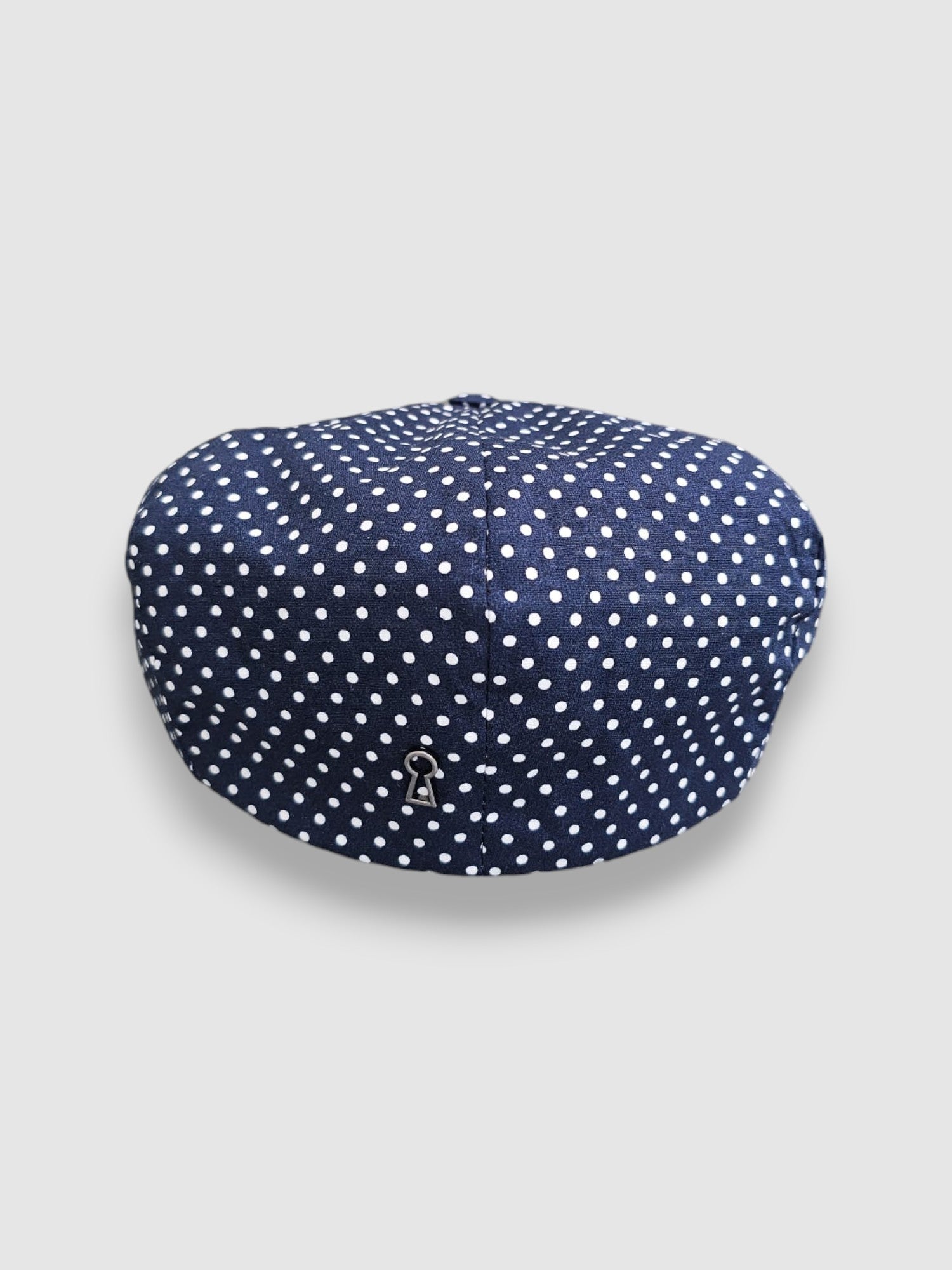 Navy blue cap with white polka dots on a light gray background