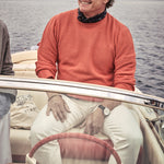 man on a riva boat wearing a newsboy cap with sunglasses