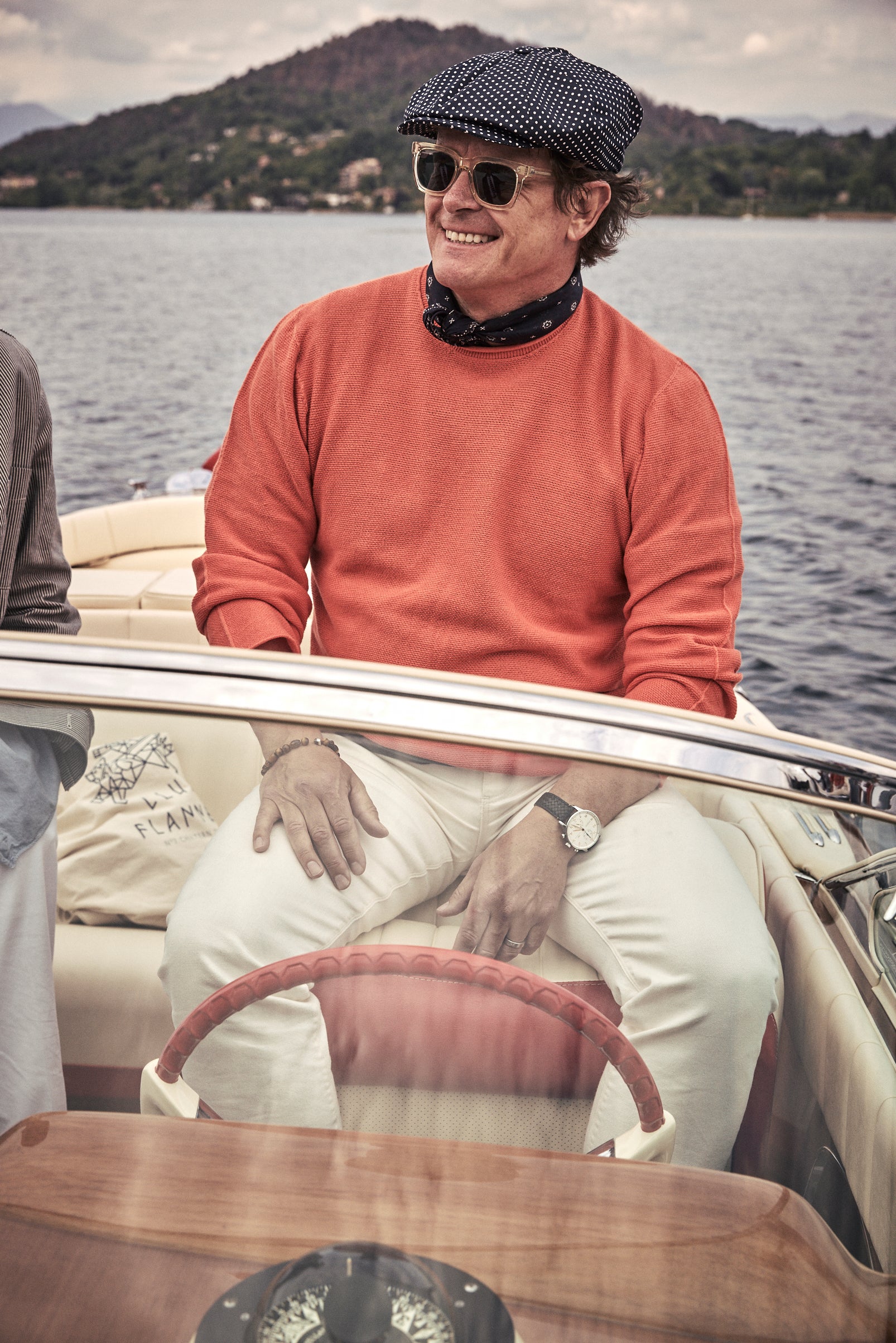 man on a riva boat wearing a newsboy cap with sunglasses